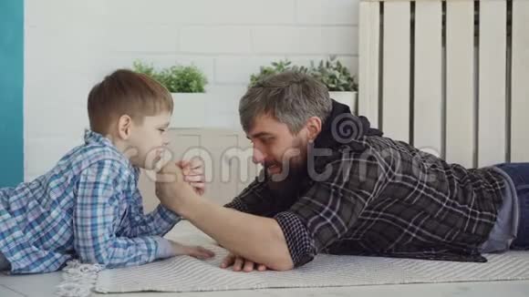 活跃的爸爸和小孩正在摔跤大人让他的儿子赢男孩高兴庆祝视频的预览图