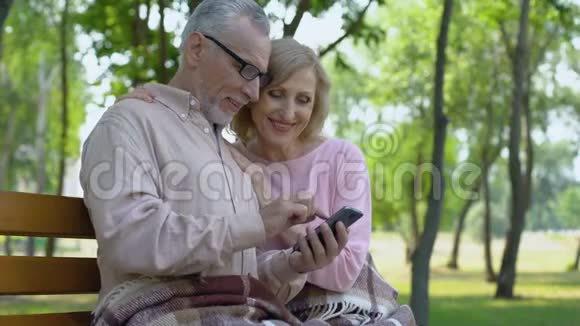 祖父和祖母欣赏智能手机应用程序中的儿童照片视频的预览图