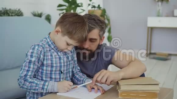 可爱的孩子初中生正在和他的父亲一起在练习本上写作业教育儿童视频的预览图