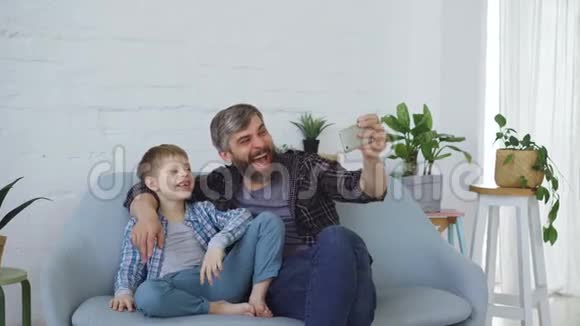 有趣的男人爱父亲正在和他开朗的儿子自拍笑着打手势摆姿势拍照自画像视频的预览图