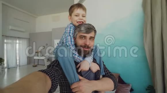 视角拍摄的胡子男和儿子坐在肩膀上录制视频自拍谈笑风生视频的预览图