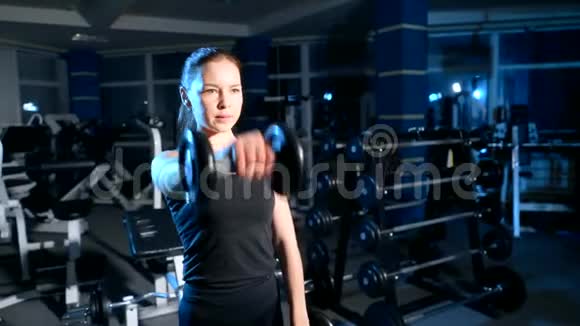 这个女孩在你面前用哑铃做一个举起手的练习视频的预览图