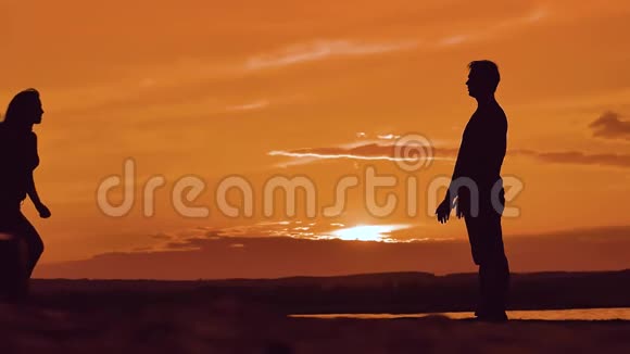 女孩在男人的脖子上奔跑和跳跃情侣在日落阳光下拥抱剪影家庭爱情概念视频的预览图