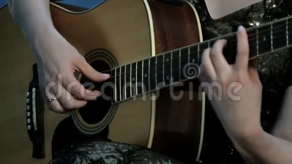专注于手指指指点点的弦一个弹声吉他的女孩的手的特写视频的预览图