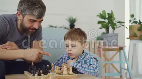 严肃的学龄前儿童正在和他的父母下棋一边想着下一步的动作一边移动奶酪视频的预览图