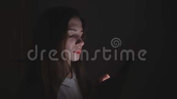 年轻女子晚上在她房间的家里使用智能手机视频的预览图