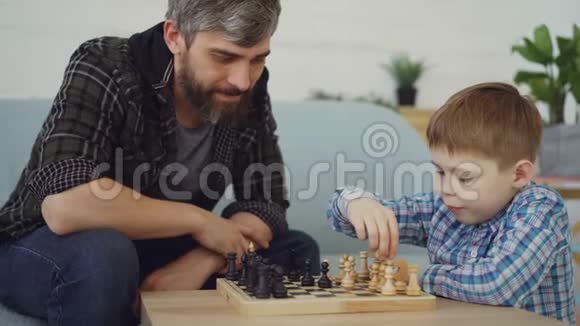 聪明的小男孩正在和他关心的父亲下棋触摸奶酪和移动的棋子智力游戏视频的预览图
