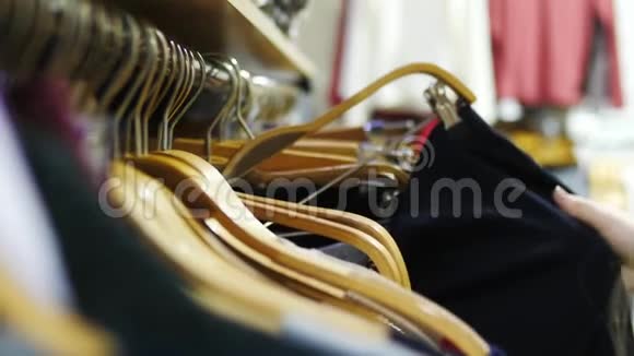 特写的女人她的手穿过一排衣服在一家精品店里浏览视频的预览图