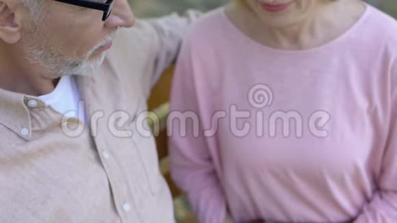 浪漫的退休夫妇交叉手指牵手户外约会公园视频的预览图