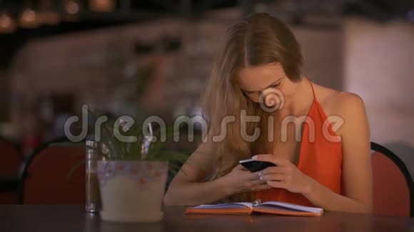 女生文本短信至朋友使用移动在咖啡厅桌视频的预览图