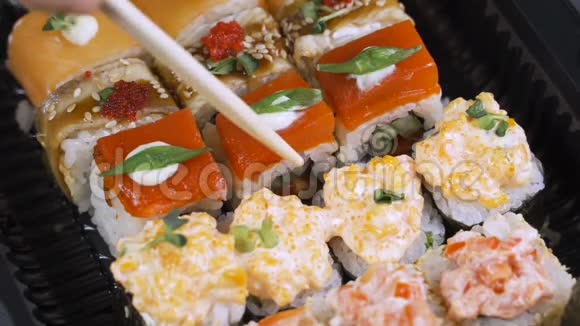 筷子的特写镜头将寿司卷在盘子或拼盘上在日本酒吧餐厅提供顶部视频的预览图