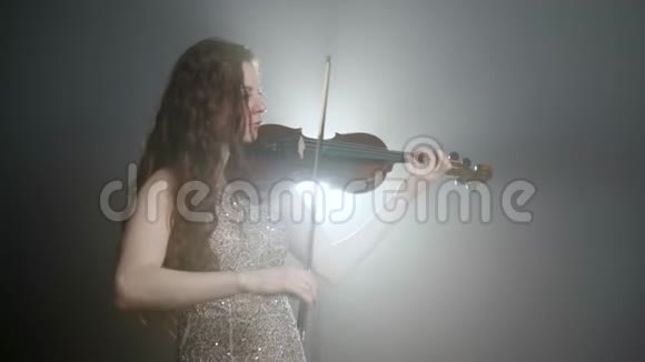 长头发的女孩在泛光照明的弦乐器上演奏古典音乐视频的预览图