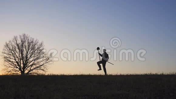 一个满意的农民在田里跳舞田野里日落或日出的剪影慢动作视频的预览图