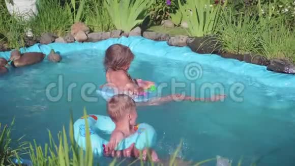 两个小朋友在一个小池塘里游泳兄妹笑泼水孩子们在炎热的夏日游泳视频的预览图