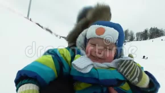 一个年轻人带着一个快乐的男孩在冬天在冰上坐过山车英俊的爸爸和儿子在笑视频的预览图
