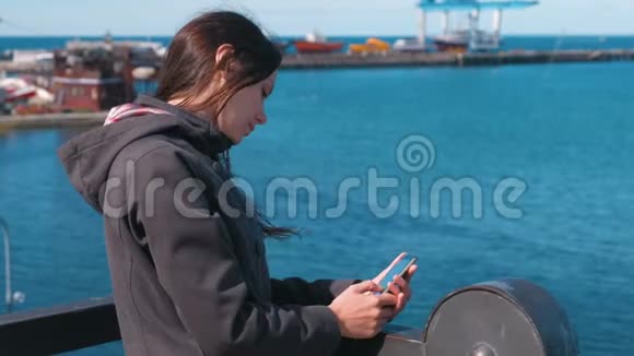 在阳光明媚的秋日布吕内特女士在海边的海边用手机输入一条信息视频的预览图