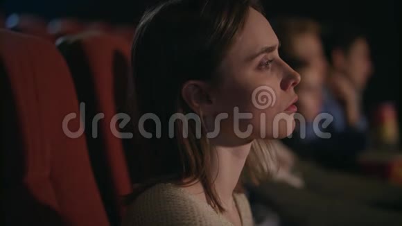 年轻女孩在电影院仔细地看电影电影里漂亮的女人脸视频的预览图