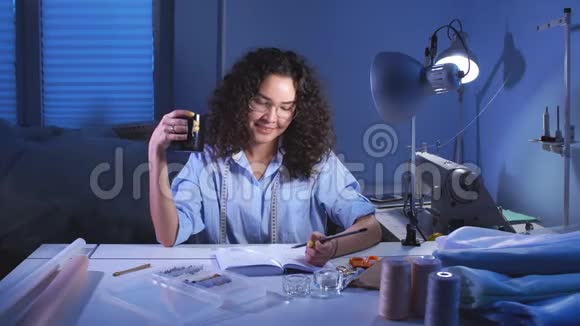 年轻的裁缝师坐在裁缝店一边喝着咖啡一边对着镜头微笑视频的预览图