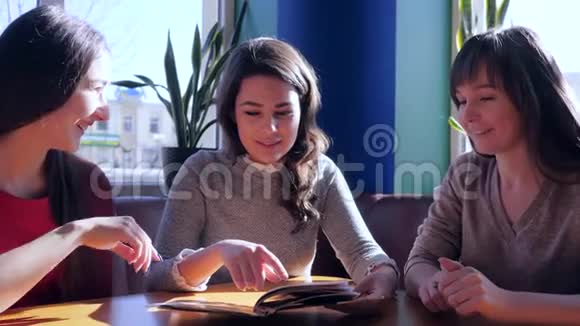 女朋友在餐厅见面微笑的女孩坐在餐桌旁看菜单视频的预览图