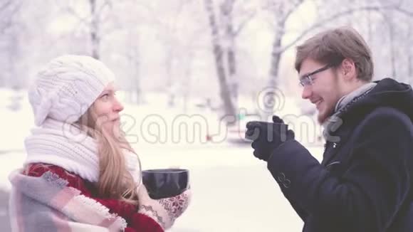 年轻的千禧年妇女戴着眼镜的长胡子男人在冬天用手捧着杯子笑着喝着热可可视频的预览图