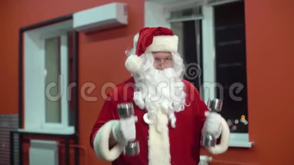 圣诞老人在健身房训练圣诞节圣诞老人正在用哑铃工作视频的预览图