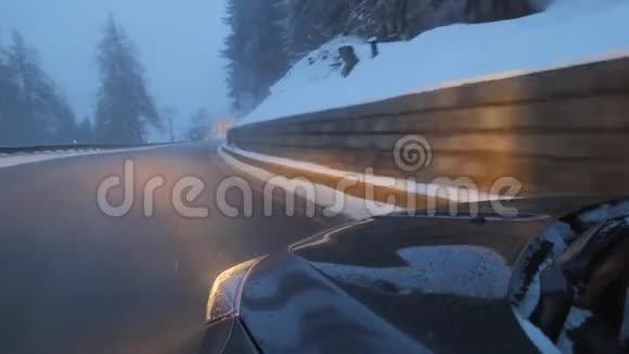 黑色现代汽车与前灯在道路上沿雪覆盖的山丘视频的预览图
