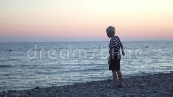 那个男孩在日落时向大海扔石头视频的预览图