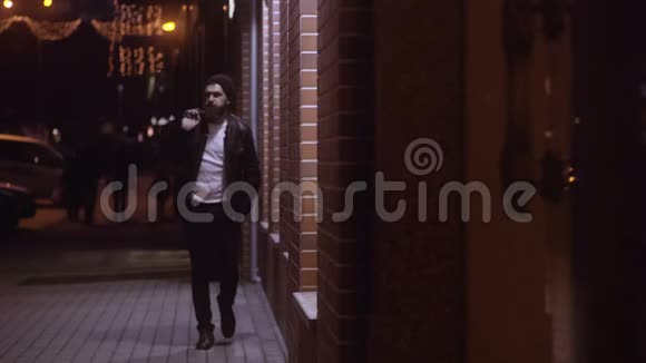 男人漫步在傍晚的城市穿过商店的窗户视频的预览图