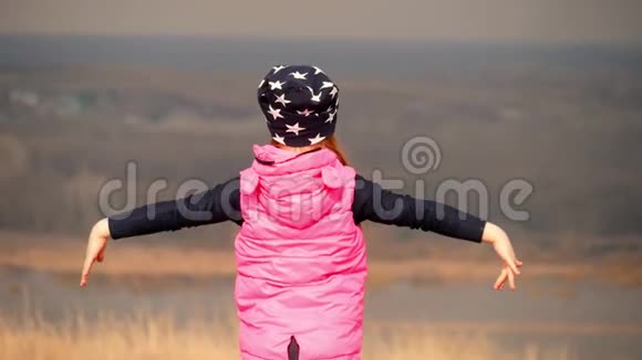 快乐的小女孩张开双手在草地上放松视频的预览图