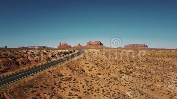 无人机在空沙岩沙漠公路上左转在亚利桑那州的纪念碑谷有史诗般平坦的山脉视频的预览图