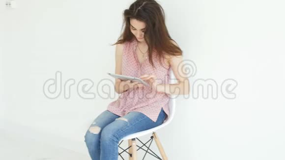 电子和个人小工具的概念年轻女子在白色室内平板电脑上阅读信息视频的预览图
