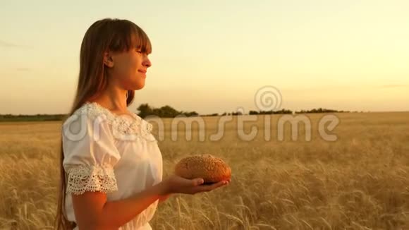 女孩手里拿着面包穿过成熟的麦田一个女孩手里拿着的面包视频的预览图
