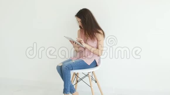 电子和个人小工具的概念年轻女子在白色室内平板电脑上阅读信息视频的预览图