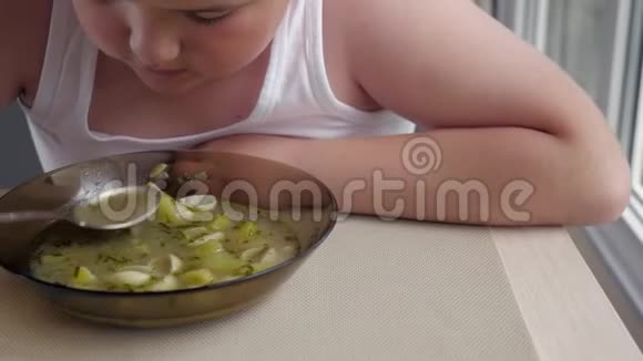有食欲的胖小子在厨房里吃汤概念肥胖的孩子视频的预览图