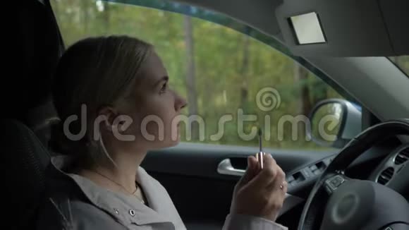 一个金发的年轻女孩坐在车里画眼睛视频的预览图