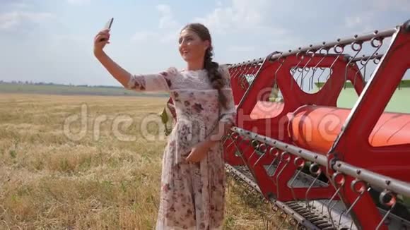 穿着衣服的农村妇女在红色农业机械附近打电话拍照视频的预览图