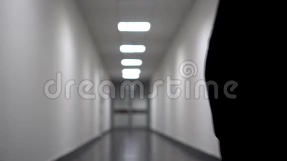 一个人沿着长长的白色走廊走去背景模糊视频包含闪烁和噪声视频的预览图