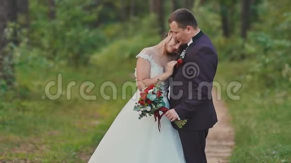 在森林里结婚新娘把头靠在新郎肩膀上一个感人的婚礼时刻视频的预览图
