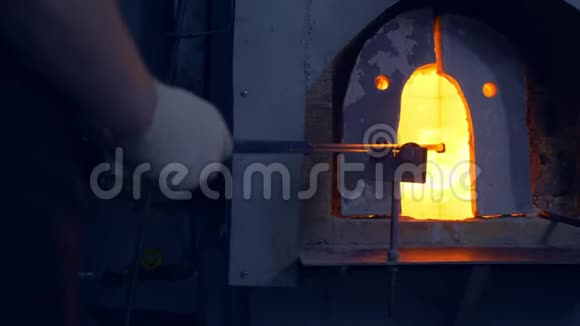 吹玻璃的玻璃产品制造商男人在炉子里加热玻璃视频的预览图
