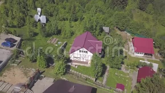 在温暖的夏天在绿色针叶林附近看到美丽的现代平房红色屋顶剪辑视频的预览图