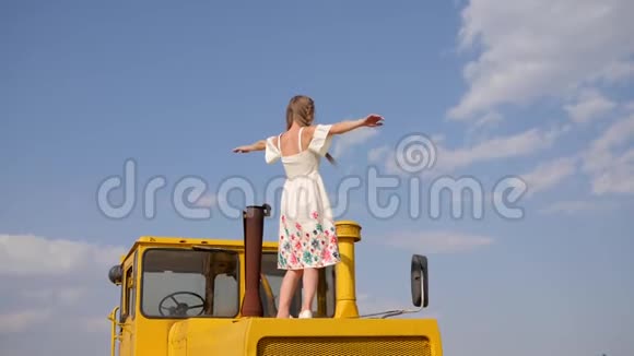 女性绕着自己转站在黄色的农机上缓慢地举起双手视频的预览图
