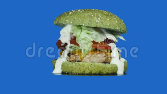 一个多汁的大汉堡夹着一个绿色的小面包里面撒着芝麻和青菜还有一个肉饼里面有酱汁视频的预览图