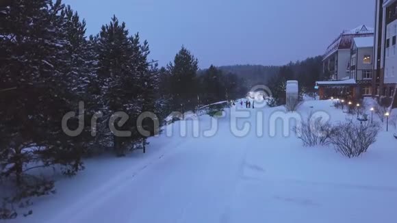 白雪皑皑的小路上有灯笼和散步的人剪辑度假胜地有公园和游客在雪地里漫步视频的预览图
