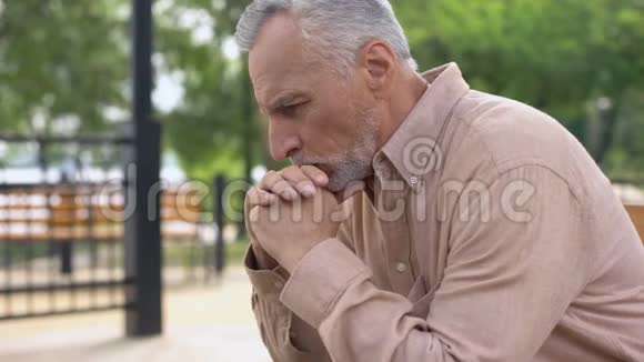 悲伤的老人坐在医院的花园长凳上老人悲伤地哭泣视频的预览图