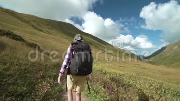 年轻的徒步旅行者朋友在山里行走带背包的旅行朋友的后后视图高清慢镜头视频的预览图