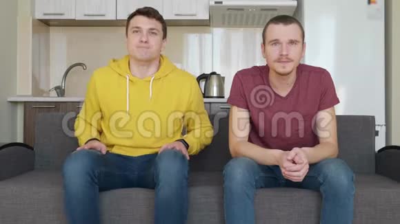 两个人坐在沙发上看电视上的足球比赛支持不同的球队视频的预览图