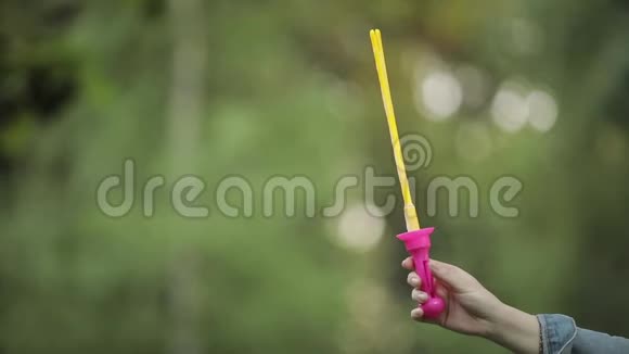 女性手握吹着闪闪发光的肥皂气泡特写慢动作视频的预览图