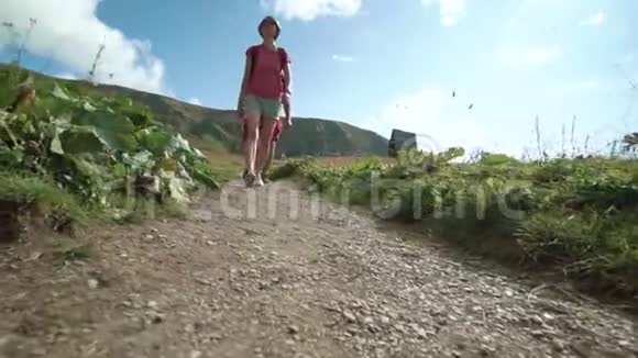 年轻的徒步旅行者朋友在山里行走带背包的旅行朋友的后后视图高清慢镜头视频的预览图