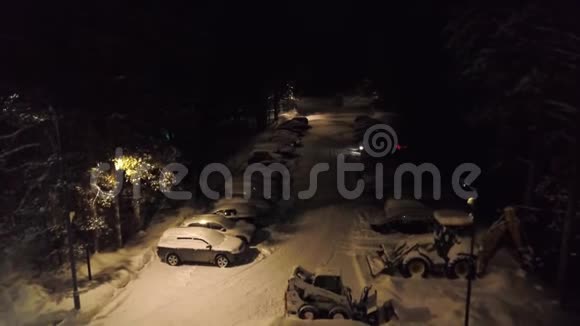 森林里白雪覆盖的停车场剪辑顶部的停车景观有覆盖积雪的汽车和站立的推土机来清扫积雪视频的预览图