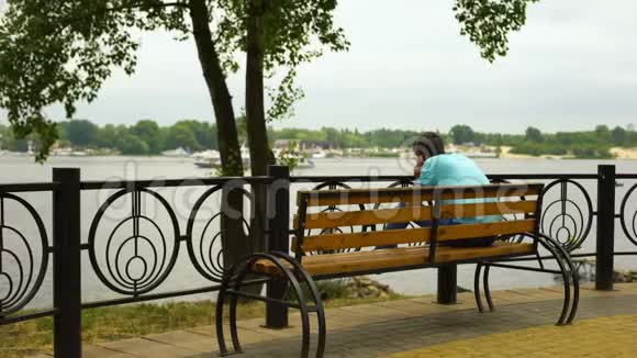 在夏季公园打电话的年轻人在河上的游艇度假视频的预览图